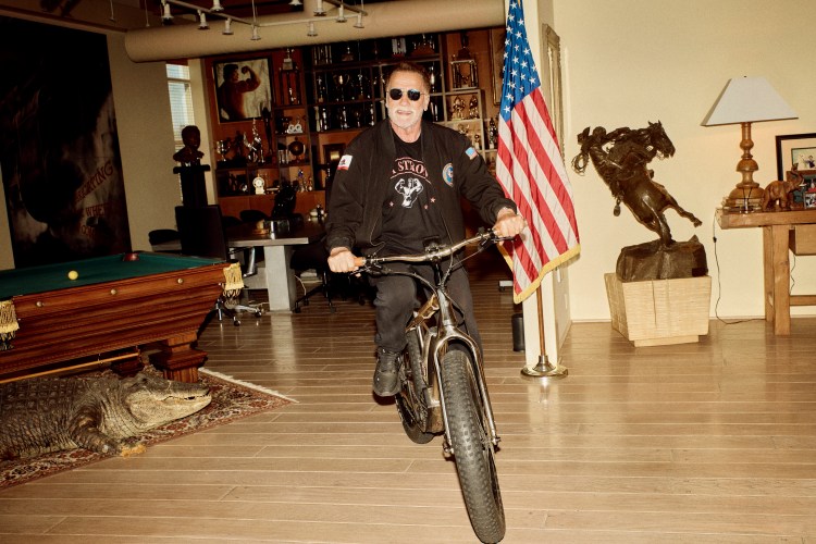 Arnold Schwarzenegger riding a bicycle in his home.